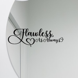 May include: Black cursive text on a white background reads "Flawless, As Always" with a heart symbol. The text is a wall decal, likely for home decor, and is displayed on a white wall next to a curved mirror.