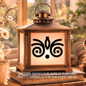Puede incluir: Una linterna cuadrada de color bronce con un asa superior y paneles de vidrio blanco. Un adhesivo de vinilo negro con un diseño simétrico de remolinos abstractos está aplicado en el panel frontal. El texto dice: LANTERN SHOWN FOR DISPLAY PURPOSES ONLY — LISTING IS FOR THE VINYL DECAL.