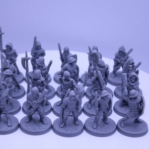 May include: A group of 15 gray plastic miniature figures of medieval soldiers, each holding a weapon and standing on a round base.