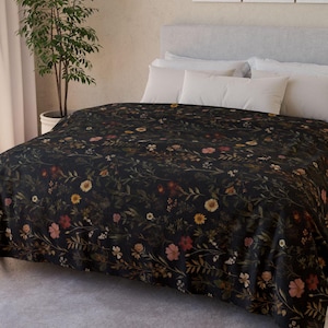 Peut inclure: Une housse de couette noire avec un motif floral présentant différentes nuances de fleurs brunes, roses et blanches. La housse de couette est sur un lit avec des oreillers blancs.