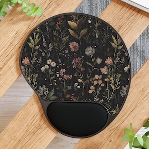 May include: A black ergonomic mouse pad with a floral design featuring various flowers in shades of pink, yellow, and white. The mouse pad has a built-in wrist rest for added comfort. The design is set against a dark background.