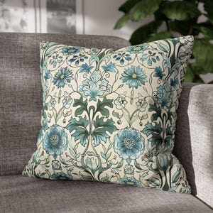 May include: A decorative cushion with a floral pattern in shades of blue, green, and cream. The cushion features a repeating design of stylised flowers and leaves.