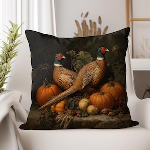 May include: Decorative throw pillow featuring a vintage still life with two pheasants, pumpkins, and gourds. The pillow has a dark background and a classic, autumnal theme. The pheasants have red, white, and black markings.
