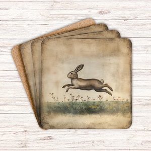 May include: Set of four brown cork coasters with a vintage illustration of a brown rabbit hopping through a field of flowers. The coasters have a distressed, aged look.