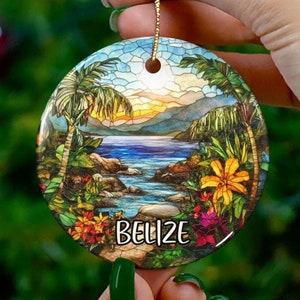 Puede incluir: Adorno redondo de cerámica con un diseño de vitral de una escena de playa tropical. El adorno presenta palmeras, un océano azul y una costa rocosa. El texto "Belize" está impreso en el adorno.