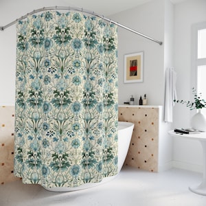 May include: A white shower curtain with a blue and green floral pattern. The shower curtain is hanging in a bathroom with a white bathtub and a tiled wall.