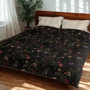 May include: A black floral duvet cover featuring a vibrant pattern of colorful flowers in shades of pink, purple, yellow, and white. The bedding is placed on a wooden bed frame with white pillows.