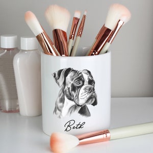 May include: White ceramic makeup brush holder featuring a black and white illustration of a boxer dog. The holder is inscribed with the name "Beth" in cursive below the dog.