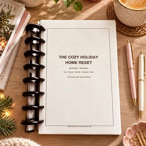 May include: A white workbook titled The Cozy Holiday Home Reset with black text and a black disc-bound spine. The cover includes the text November + December, Plan - Prepare - Simplify - Celebrate - Reset, and Ink-Friendly Half Letter Workbook.