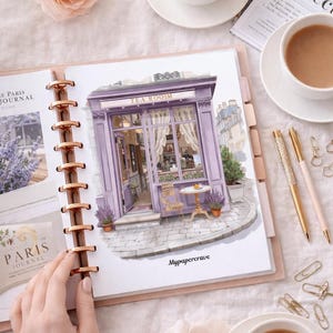Può includere: Un'agenda a dischi aperta su una pagina con un'illustrazione ad acquerello di una sala da tè viola con il testo Mypapercrave. La pagina include un'intestazione Paris Journal, immagini di lavanda, un tavolo e una sedia. Due penne dorate e graffette sono nelle vicinanze.