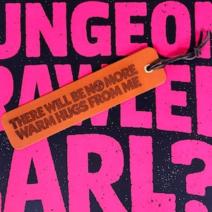 Könnte beinhalten: Ein rechteckiges Lesezeichen aus hellbraunem Leder mit einer dunkelbraunen, lasergravierten Inschrift: THERE WILL BE NO MORE WARM HUGS FROM ME. Das Lesezeichen verfügt über eine Metallöse und ein dünnes, dunkelbraunes Lederband an der oberen Ecke.