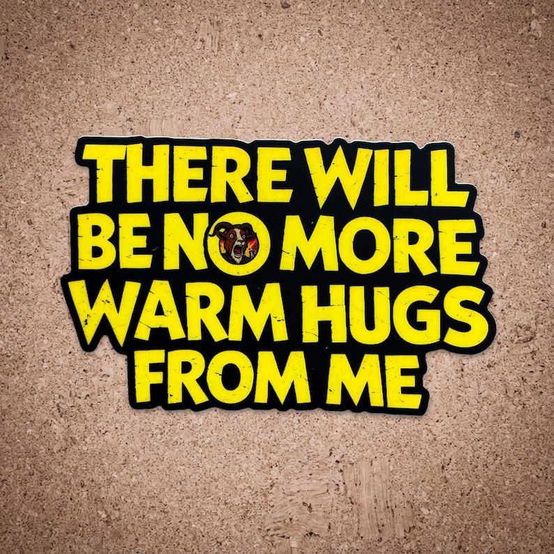 以下が含まれることがあります： 「THERE WILL BE NO MORE WARM HUGS FROM ME」と書かれた黄色の文字が特徴の黒いステッカー。ステッカーは使い古されたような外観で、中央に雄羊の頭の小さなグラフィックがあります。