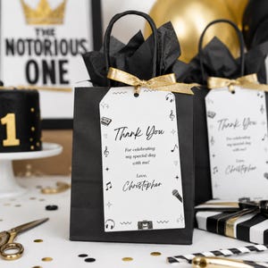 Può includere: Sacchetti regalo neri con nastri dorati ed etichette con la scritta "Grazie". Le etichette hanno note musicali e una grafica a cassetta. Il testo sull'etichetta dice "Per aver celebrato il mio giorno speciale con me! Amore, Christopher."