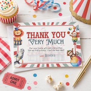 Op de afbeelding: Een circus-thema bedankkaart met de tekst "THANK YOU VERY MUCH" en illustraties van een leeuw, een zeehond, een clown en een aap. De kaart bevat de tekst "For your lovely gift and kind wishes for my 3rd birthday. I had the best day!" en "LOVE, OLIVER'S".