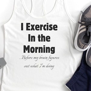 May include: White tank top with the text "I Exercise In the Morning...Before my brain figures out what I'm doing". The tank top is laying on a white surface with a pair of gray dumbbells and a pair of gray running shoes.