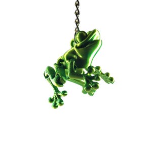 May include: A green frog keychain with a chain attached to its back. The frog is smiling and has its legs outstretched.