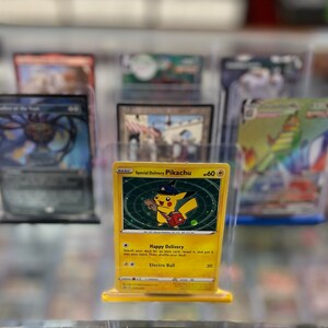 May include: A yellow Pokemon trading card featuring Pikachu with a hat and a package. The card is titled "Special Delivery Pikachu" and has a power of 60. The card has an attack called "Happy Delivery" and another attack called "Electro Ball" with a power of 30.