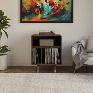 May include: A dark wood record player stand with a top surface holding a turntable, a middle shelf containing a Marshall speaker, and two lower compartments filled with vinyl records. The stand features four short legs with gold-toned accents.