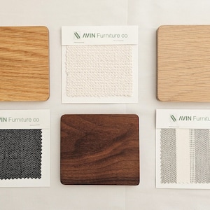 May include: Six fabric and wood samples for furniture upholstery. The samples include a white fabric, a gray and white striped fabric, a black and gray herringbone fabric, a light wood sample, a dark wood sample, and a light brown wood sample. Each sample is labeled with the text "AVIN Furniture co."