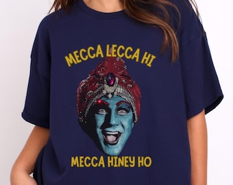 Puede incluir: Una camiseta azul marino con un gráfico de un hombre con turbante con el texto "Mecca Lecca Hi" y "Mecca Hiney Ho" impreso en amarillo.