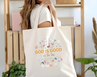 May include: A white canvas tote bag with a floral design and the text "GOD IS GOOD all the time" in orange.