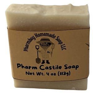 Può includere: Una saponetta rettangolare di Pharm Castile, avvolta in un'etichetta di carta marrone. L'etichetta presenta un personaggio dei cartoni animati con una pala e un forcone, e il testo "Pharmboy Homemade Soap LLC". Il sapone pesa 113g.