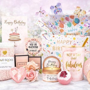 May include: A gift box filled with birthday-themed items. Includes a mug with "Not a day over fabulous", a candle, bath bomb, socks, a card, and a compact mirror. The box is decorated with butterflies and balloons.