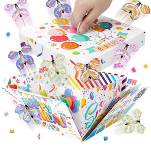 May include: A white square gift box with a Happy Birthday print and colorful balloons, featuring multiple flying butterfly toys that spring out from the sides. The box has a lid with a balloon design and interior panels decorated with stars and confetti.