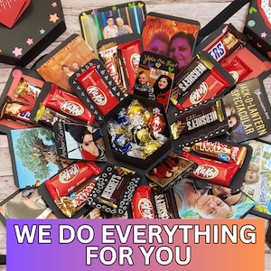 May include: A black explosion box filled with photos, chocolates, and sweets. The box is decorated with stars and hearts. The text "WE DO EVERYTHING FOR YOU" is displayed at the bottom. Chocolate brands include Kit Kat, Hershey's, and Twix.