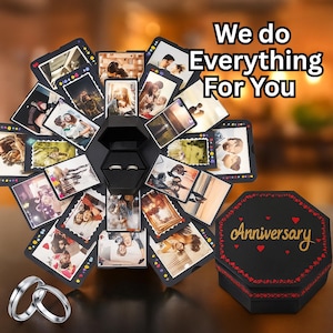 May include: Black explosion box with photos, two rings, and the text "We do Everything For You." The box is open, revealing photos and a ring box. A separate box says "Anniversary."