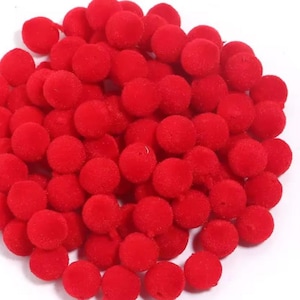 以下が含まれることがあります： 小さくて丸い、鮮やかな赤色のポンポンの山。これらの柔らかくふわふわしたボールは、白い背景に集まっています。工芸品、装飾、または装飾に使用される可能性があります。