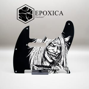 Könnte beinhalten: Schwarzes Gitarren-Schlagbrett mit einer weißen Illustration eines Monsters mit langen Haaren, scharfen Zähnen und einem Messer. Das Schlagbrett trägt den Text "EPOXICA Guitars" und ein Logo.