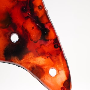 Puede incluir: Primer plano de una obra de arte abstracta roja y negra con dos agujeros circulares. La obra de arte tiene un acabado brillante y un dise&ntilde;o org&aacute;nico &uacute;nico. Los colores se mezclan, creando un efecto visualmente impactante.