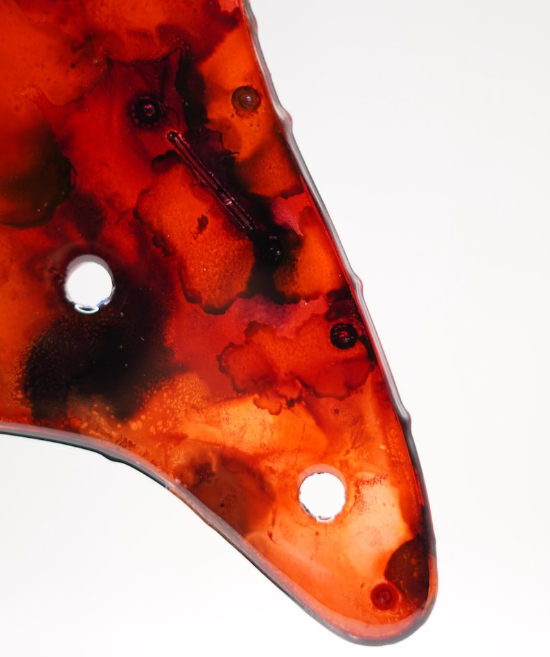 Puede incluir: Primer plano de una obra de arte abstracta roja y negra con dos agujeros circulares. La obra de arte tiene un acabado brillante y un dise&ntilde;o org&aacute;nico &uacute;nico. Los colores se mezclan, creando un efecto visualmente impactante.