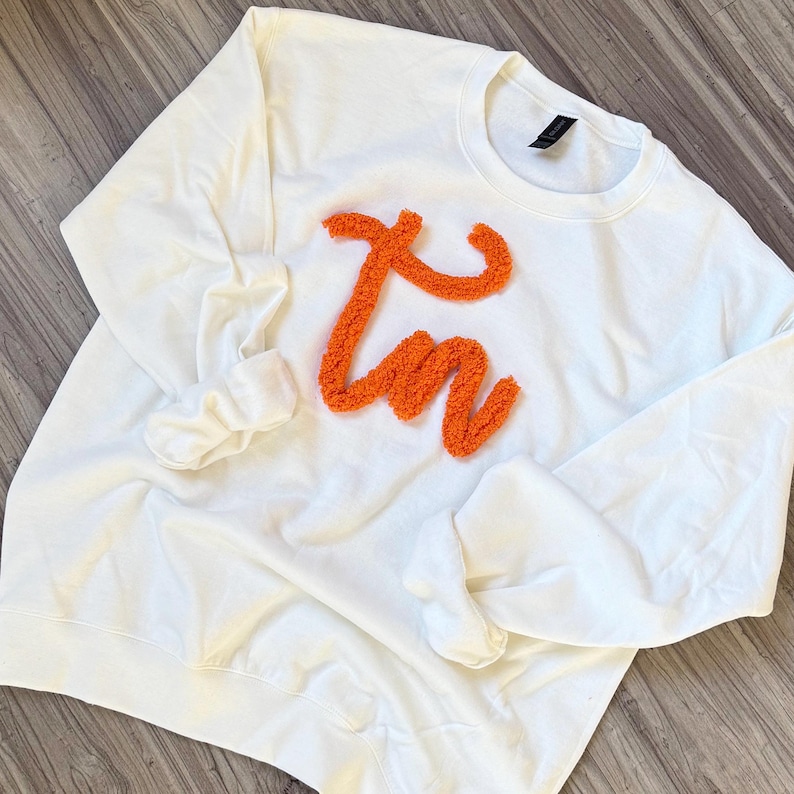 May include: White sweatshirt with a large orange fluffy "I'm" design.
