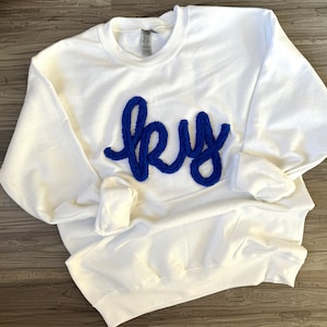 May include: White sweatshirt with a blue fuzzy applique that says "sky".