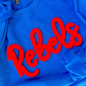 May include: A royal blue sweatshirt with a red fuzzy applique that says "Rebels".