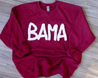 May include: A maroon sweatshirt with the word "BAMA" in white fluffy letters.