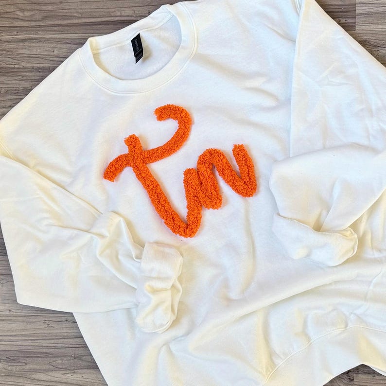 May include: White sweatshirt with a large orange fluffy "I'm" design.