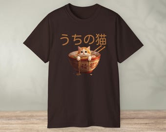 May include: Brown t-shirt featuring a graphic of a cat in a ramen bowl with chopsticks. The text "うちの猫" is above the bowl. The cat is orange and white, and the bowl is red and gold.