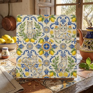 May include: A square decorative tile featuring a repeating pattern of cats, yellow lemons, and blue scrollwork on a cream background. The design includes cats in various poses surrounded by green leaves and citrus fruit, arranged in a grid layout.
