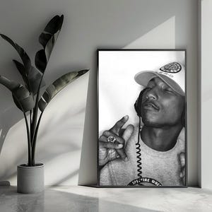 Puede incluir: Fotografía en blanco y negro de un retrato de una persona que lleva un sombrero con el texto "SPITFIRE WHE". La persona lleva una camisa gris y tiene los ojos cerrados.