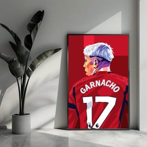 Könnte beinhalten: Eine digitale Illustration eines Fußballspielers, der ein rotes Trikot mit dem Namen "GARNACHO" und der Nummer "17" auf dem Rücken trägt. Der Spieler hat kurze, weiße Haare und schaut zur Seite.