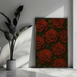 Può includere: Una stampa incorniciata con un motivo di rose rosse con foglie verdi. Le rose sono in piena fioritura e hanno una consistenza vellutata. L'opera d'arte è esposta accanto a una pianta in vaso.