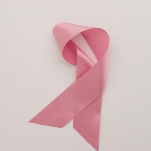 May include: A pink ribbon, a symbol of breast cancer awareness.