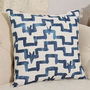 May include: Blue and white geometric patterned throw pillow with a linen texture.