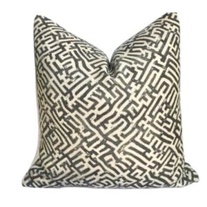 May include: A square cushion featuring a cream-coloured backdrop and a repeating black maze-like design. The cushion is soft and plush, ideal for adding a touch of style to any room.