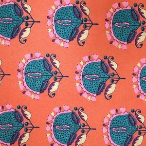 Peut inclure: Un tissu orange avec un motif floral répété. Chaque motif présente un centre turquoise avec des détails roses, jaunes et violets, créant un textile vibrant et accrocheur.