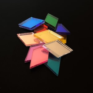 May include: A collection of colorful, diamond-shaped glass tiles in various hues, including blue, green, red, yellow, pink, and gold. The tiles are arranged on a black surface, creating a vibrant and reflective display. These tiles could be used for mosaics or decorative projects.