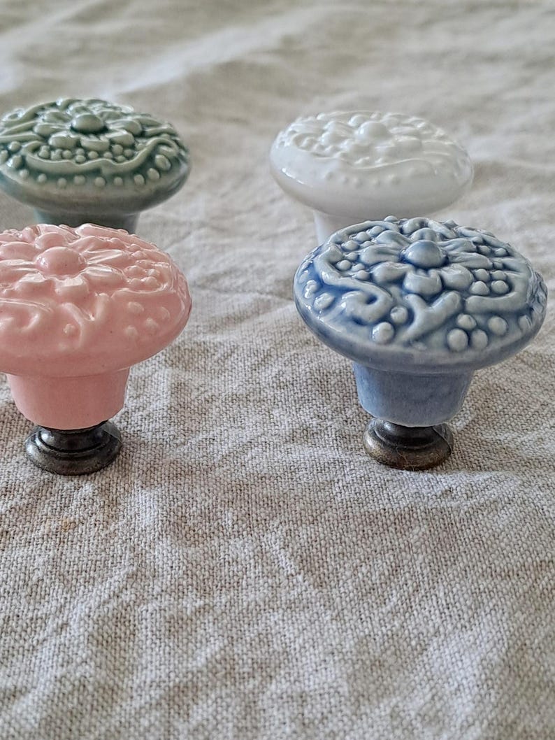 May include: Four ceramic cabinet knobs with a floral design. The knobs are in shades of green, white, pink, and blue.